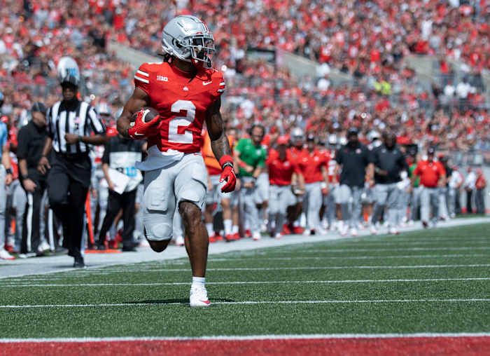 Emeka Egbuka runs with the ball in one hand while looking over his shoulder